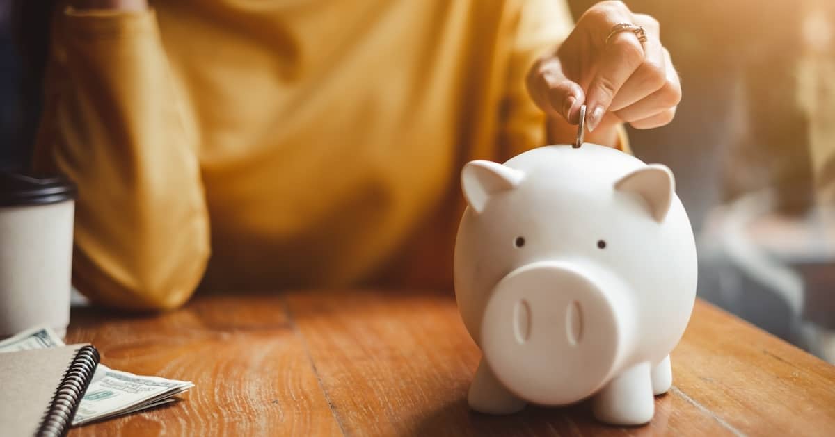 Woman putting money in a piggy bank to save up for the cost of LASIK