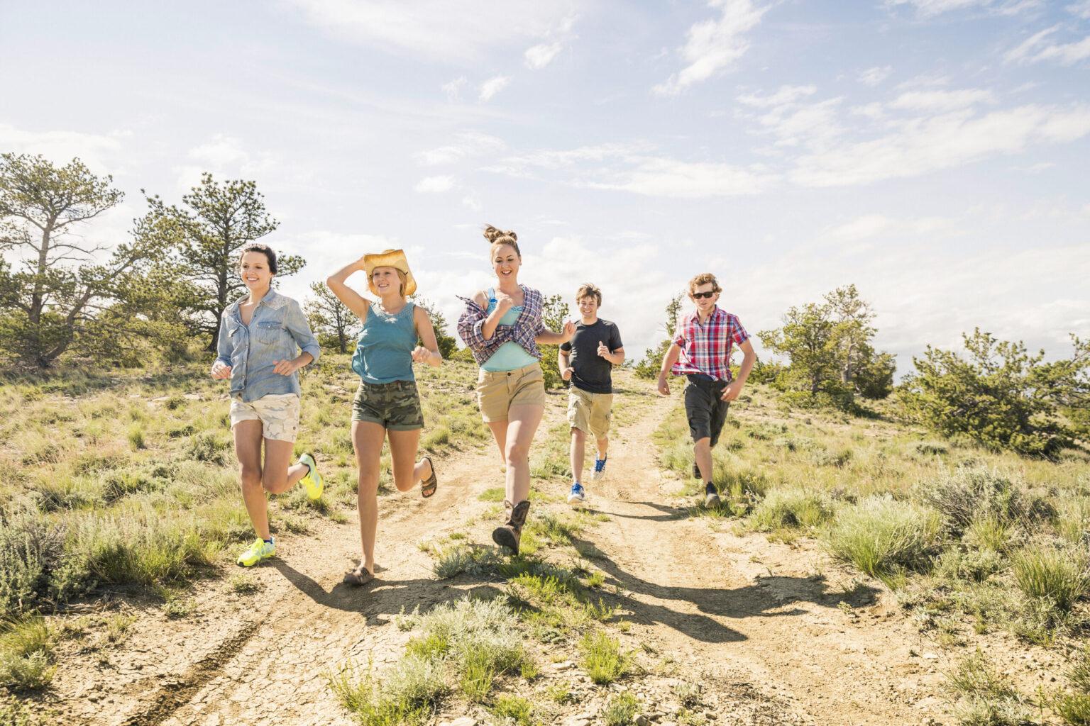 Teenage girl and adult friends running on dirt track, Bridger, Montana, USA